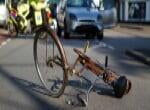 Bicycle lying on the road with a car in the background